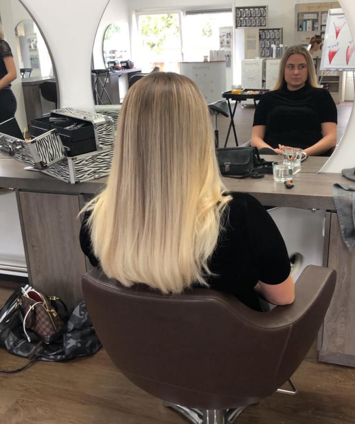 Blonde balayage in de salonstoel, met het interieur op de achtergrond