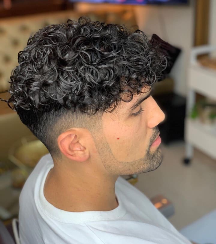 Man met krullen bovenop en een strakke fade aan de zijkanten