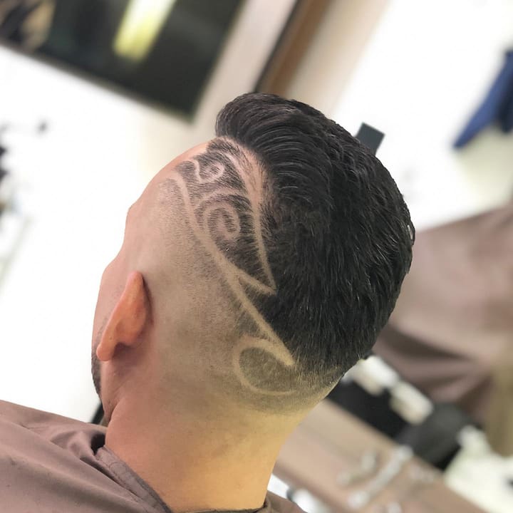 Hair tattoo: een sierlijk lijnenpatroon geschoren in de fade aan de achterkant van het hoofd